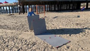 Une personne déplie des dalle Access Trax sur une plage de sable