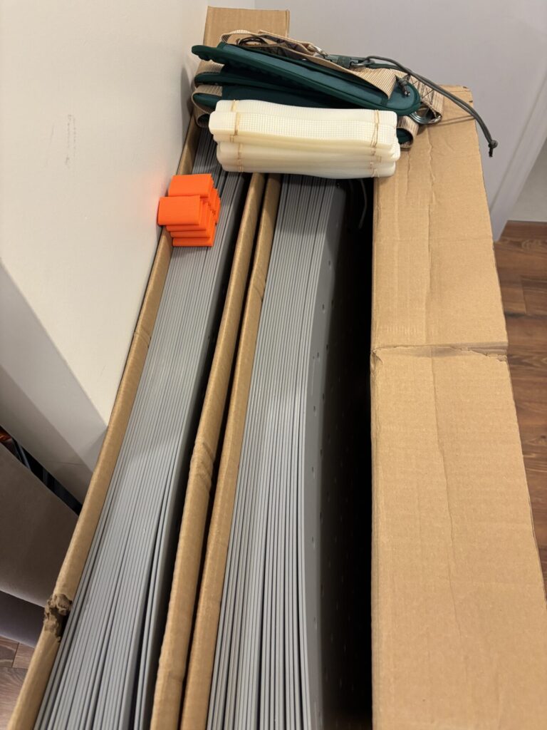 Two large open cardboard boxes reveal their contents: Access Trax mats with on the top of them, transport straps, anti-slip strips, and carrying straps