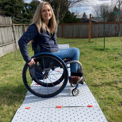 Une femme est dans un fauteuil roulant, sur un Access Trax, sur de l'herbe