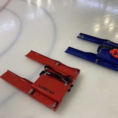 Un Lugicap Ice Perf rouge et un bleu sur la glace d'un arena / A red Lugicap Ice Perf next to a blue on the ice of an arena